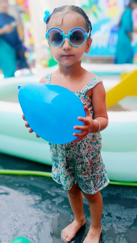 Student holding blue balloon at pool event